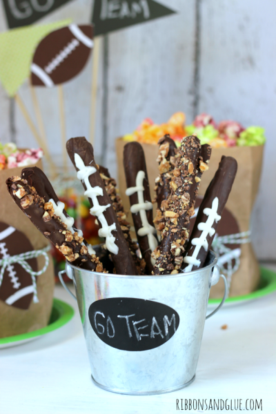 Quick and Easy Superbowl Chocolate Football Pretzel Sticks. Dip pretzel sticks in to melted chocolate and sprinkle with crushed candy bars and make football stitching with white melting candy. 